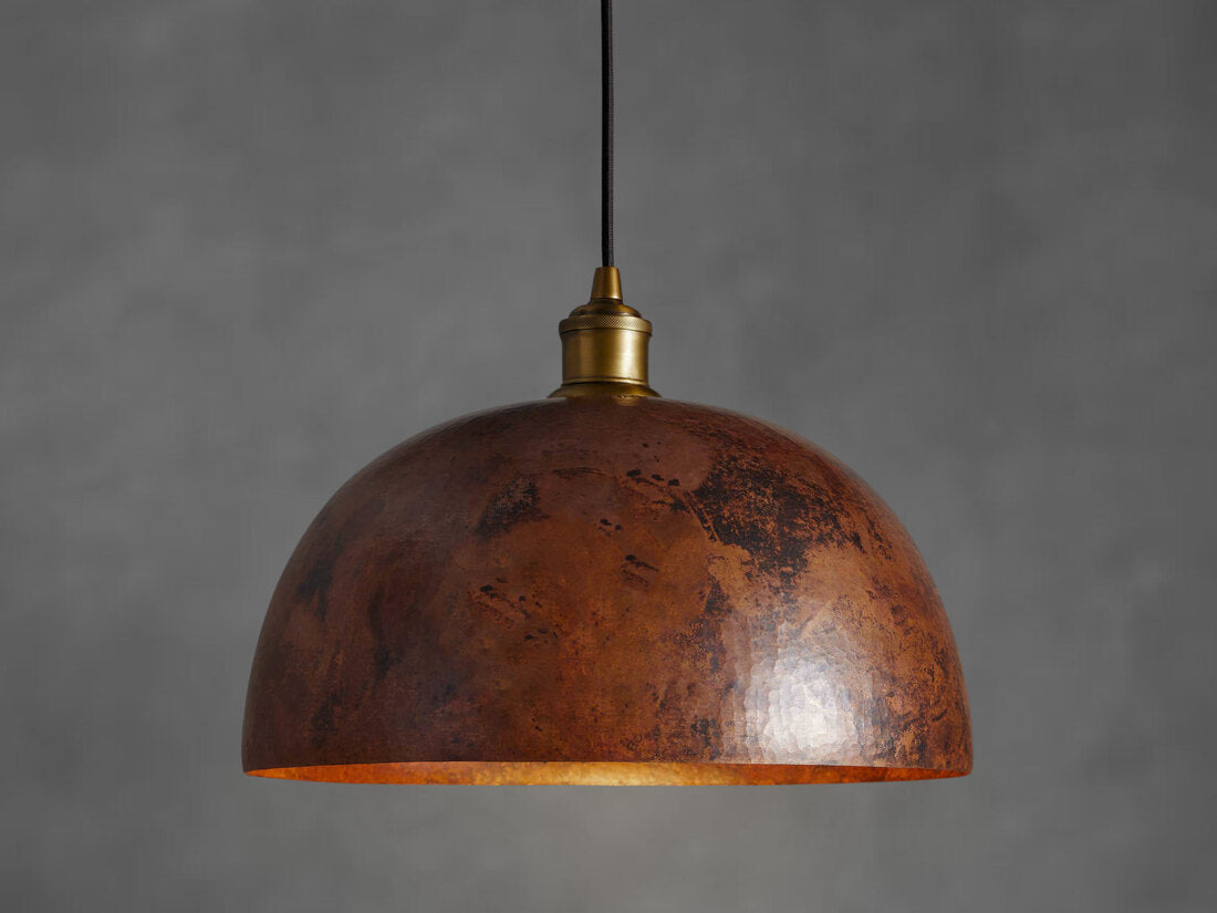 A copper dome pendant light elegantly suspended from the ceiling, showcasing its unique design and finish.